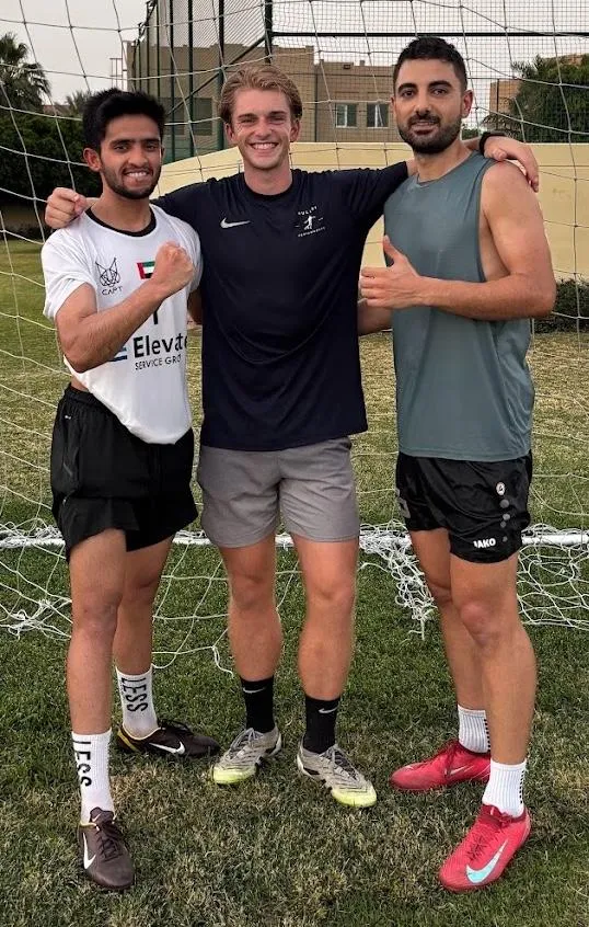 Ethan Hulley with two players he coaches on a Dubai pitch